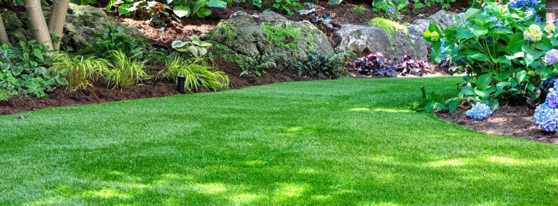 Lush garden with manicured lawn and flowering shrubs.